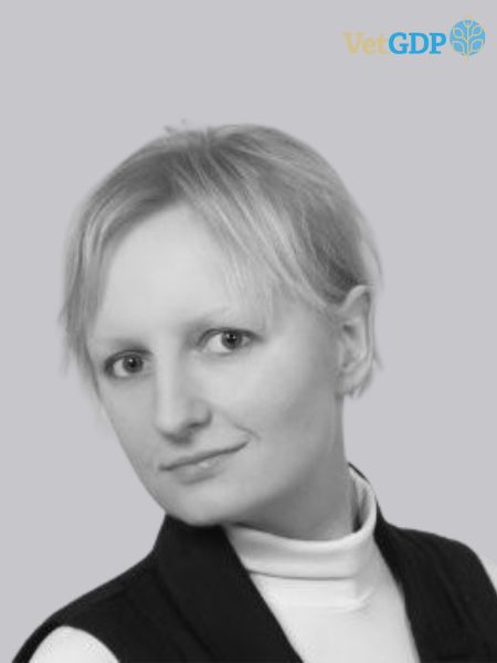 A black and white photo shows a person with short light-coloured hair, wearing a white turtleneck and a dark vest. The VetGDP logo is in the top right corner.