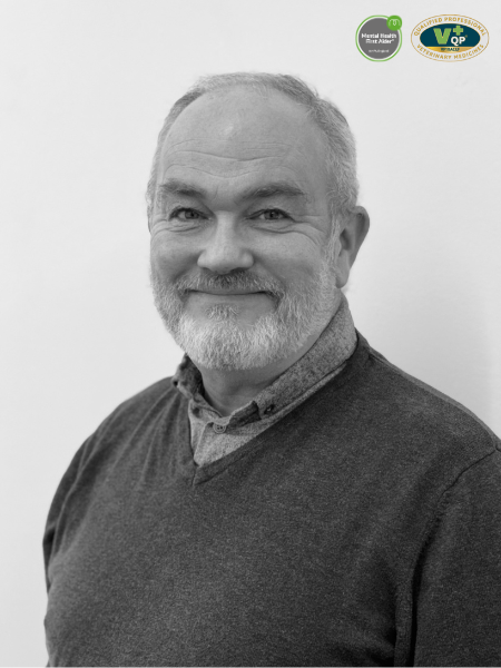 A black and white photo shows an elderly man with grey hair and a beard. He wears a jumper over a shirt and is smiling at the camera. Two logos are in the top right corner.