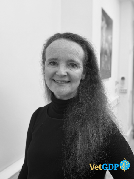 A woman with long, wavy hair is indoors, wearing a black polo neck and smiling at the camera. The VetGDP logo appears in the bottom right corner.