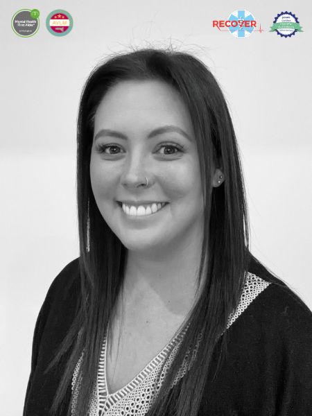 A black and white photo shows a woman with long dark hair, smiling at the camera. At the top of the picture, there are four certification logos.