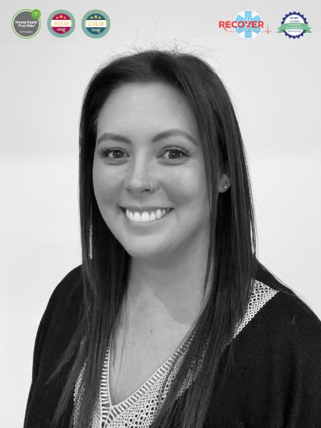 A black and white photo shows a woman with straight hair, a nose ring, and a warm smile. At the top of the picture, there are four badges for awards or certificates.